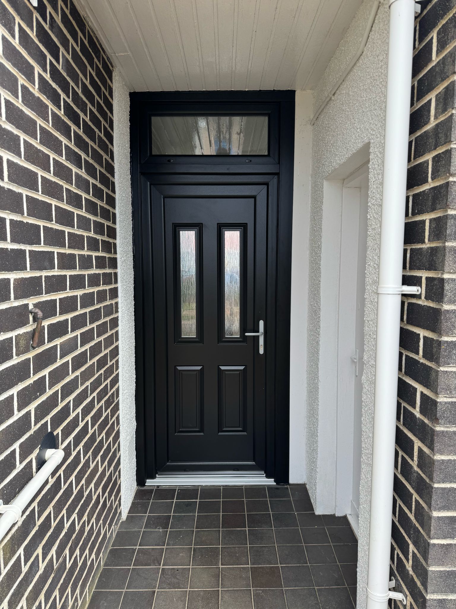 Black UPVC front and back doors with satin chrome hardware, recently installed in a West Kilbride home to replace traditional timber doors.